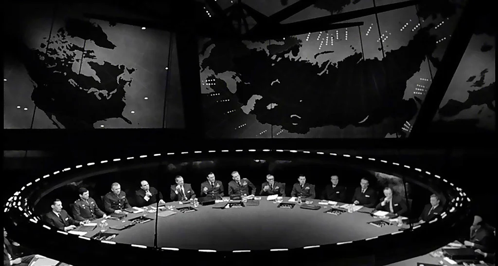 Officials seated around a war-room table beneath glowing world maps